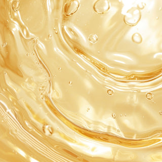 Close-up of golden skincare serum or oil with bubbles, highlighting rich texture and luminous glow.